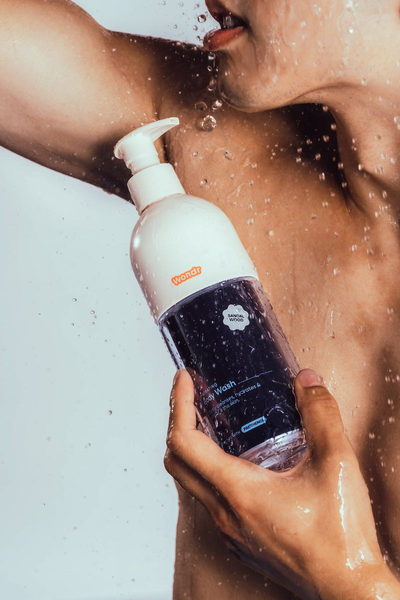 Waterdruppels op de huid, met de fles WONDR Liquids body wash in de hand