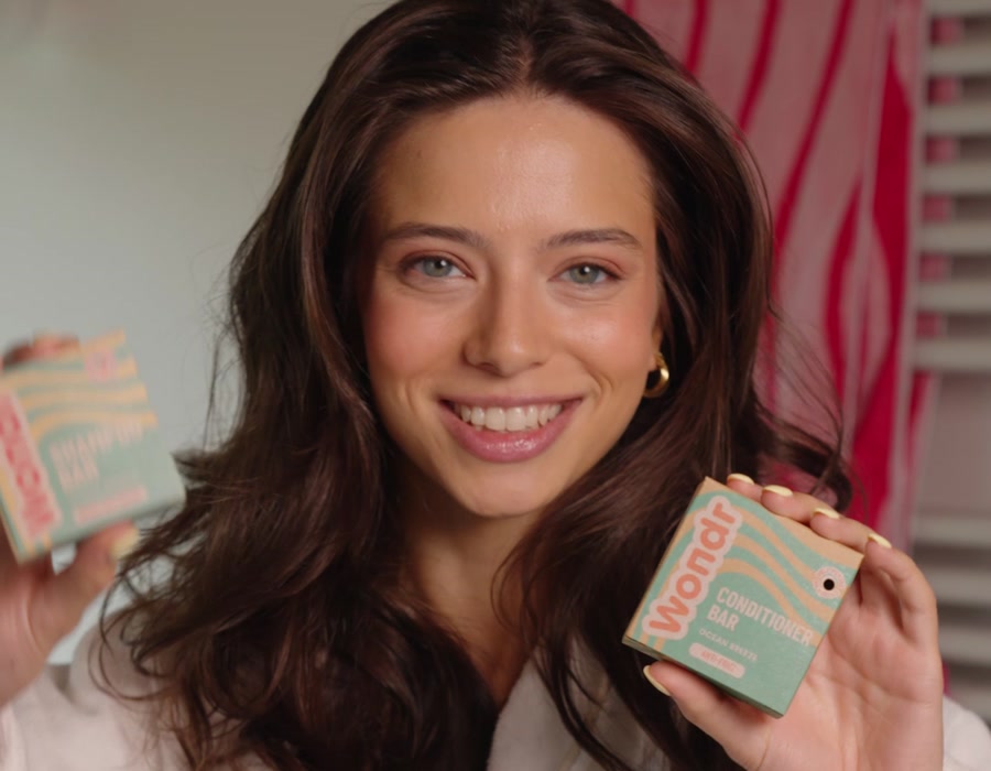 Vrouw met glanzend haar houdt de Ocean Breeze shampoo bar en conditioner bar vast